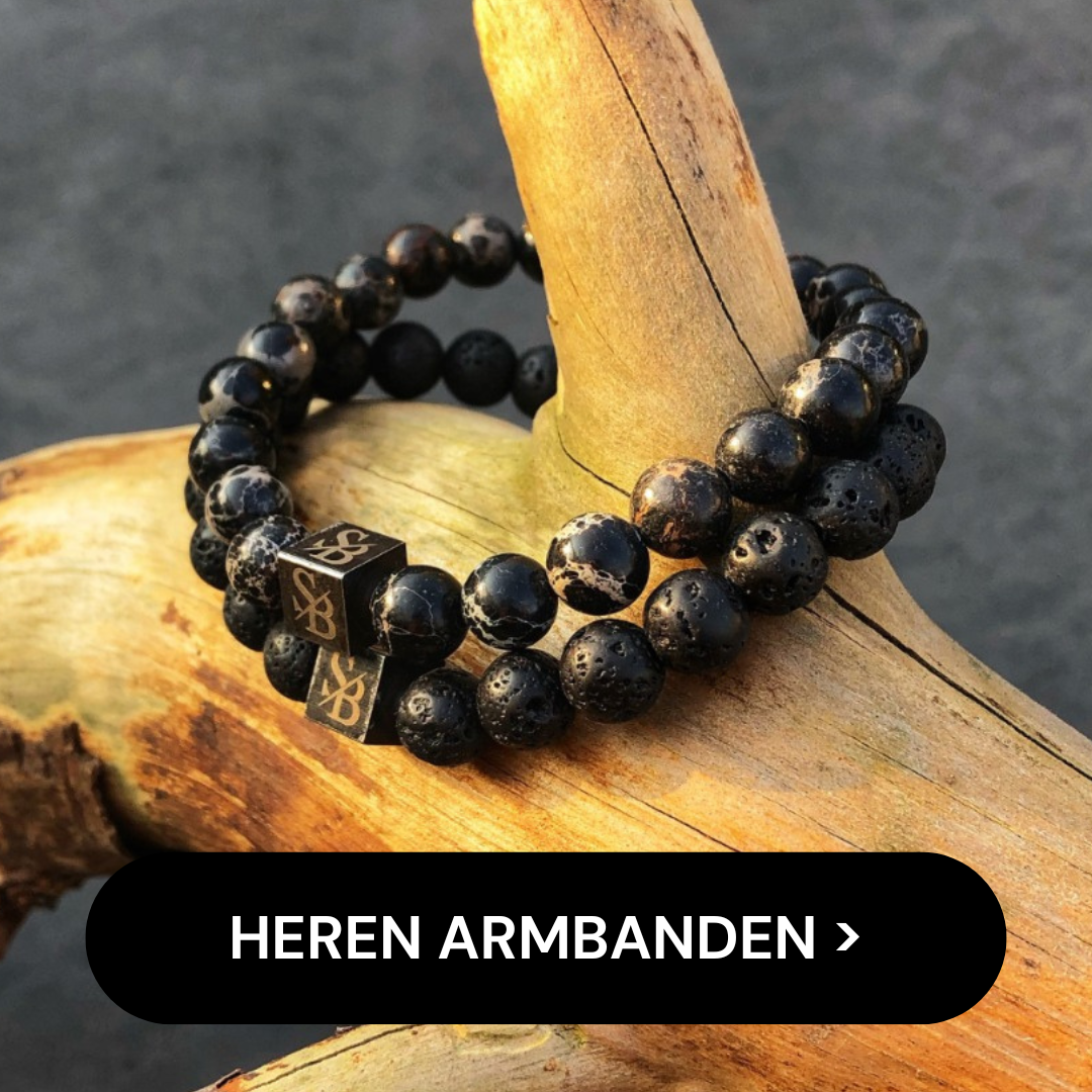 Een set van twee zwarte kralenarmbanden met vierkante bedeldetails is op deze afbeelding om een boomstam gewikkeld, met natuursteenelementen. Een zwarte knoop met witte tekst onderaan luidt "HEREN ARMBANDEN".