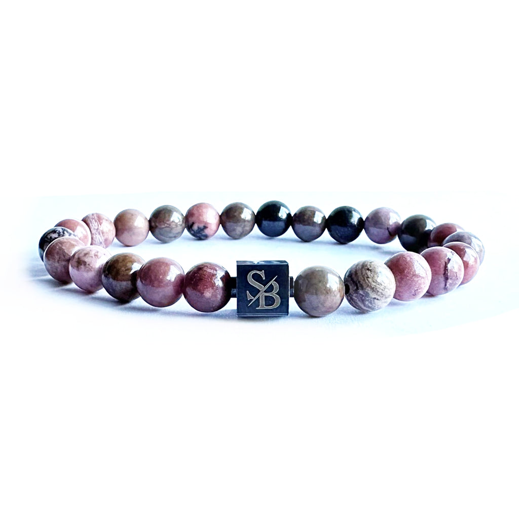 Ontdek de delicate charme van de Black Rhodoniet armband. Deze roze gekleurde armband, vervaardigd van de natuursteen Rhodoniet, straalt elegantie en schoonheid uit. Laat je betoveren door de zachte tinten en unieke patronen van deze prachtige natuursteen.
