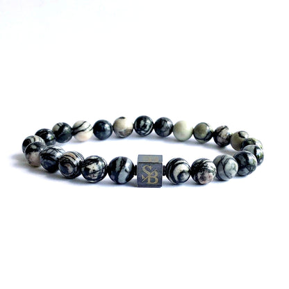 Omarm de tijdloze elegantie van de Black Silk Stones armband. Gemaakt van zwarte netwerk agaat, betovert deze armband met zijn serene grijze tint. Laat je verleiden door de fijne schoonheid van deze natuursteen, geweven in een stijlvol accessoire dat je outfit complementeert.