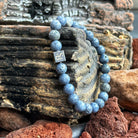 Een blauwe Stoney Bracelets koraalstenen (8 mm) armband zit bovenop rotsen.