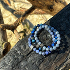 Een blauw-witte Stoney Bracelets-armband rustend op een stuk hout.