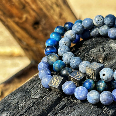 Twee Stoney Armbanden met blauwe stenen bovenop een houten tafel.