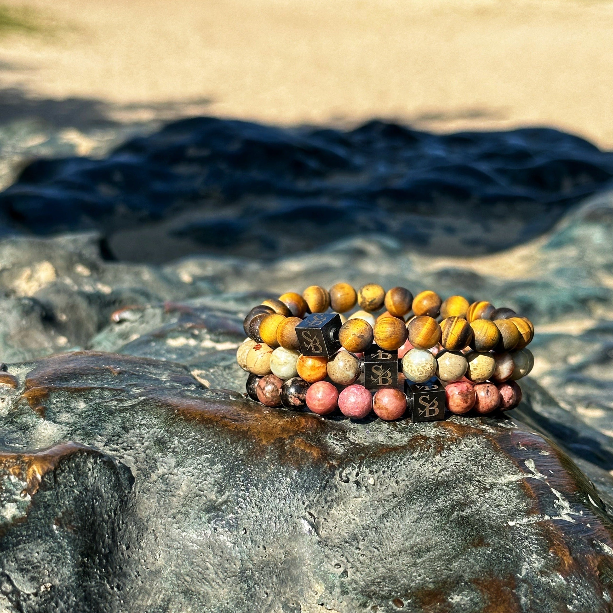 Een Tropical Set (8mm) armband van Stoney Bracelets ligt op een steen.