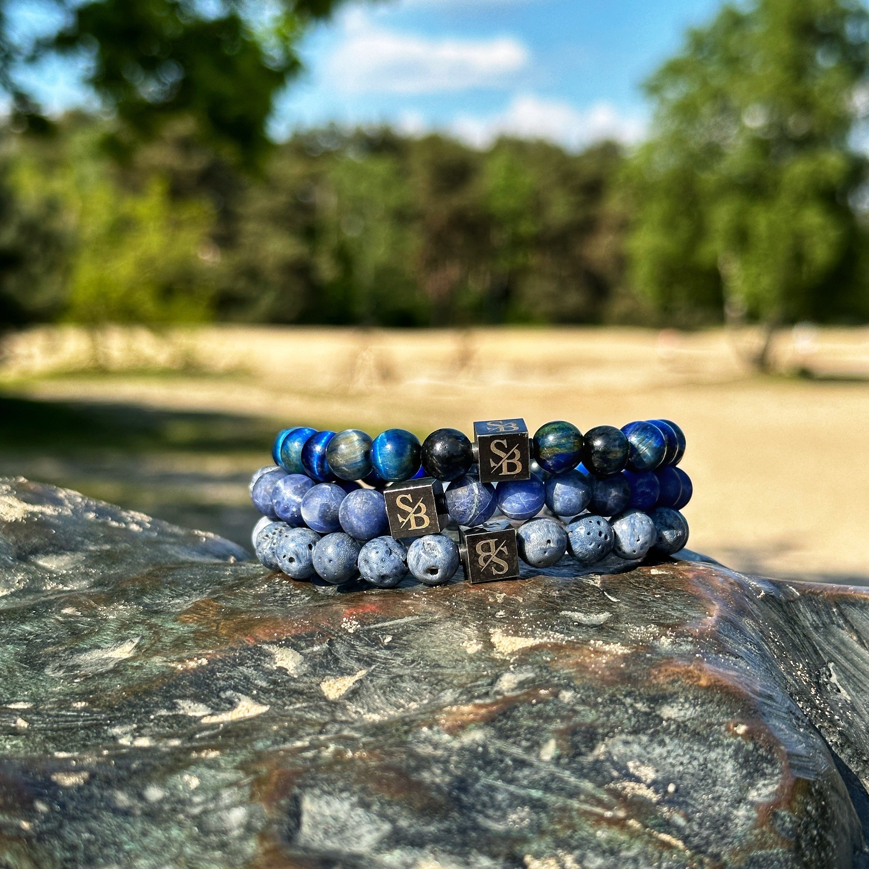 Twee Pacific Set (8mm) armbanden met blauwe stenen bovenop een rots van Stoney Bracelets.