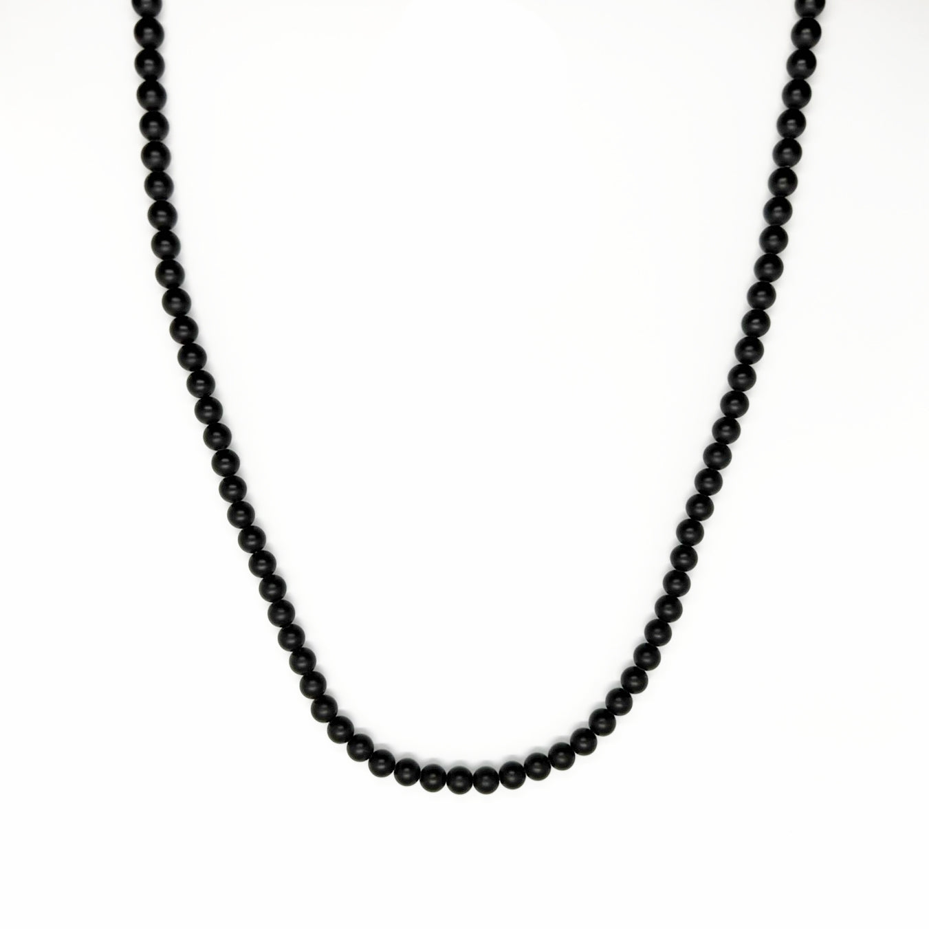 De Matte Obsidian Necklace (6mm) van Stoney Bracelets heeft een streng van uniforme, gladde kralen tegen een witte achtergrond. De doorlopende lus omarmt minimalistische stijl en symboliseert bescherming.