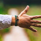 Een hand versierd met Stoney-armbanden met hun malachietgroene stenen (8 mm).