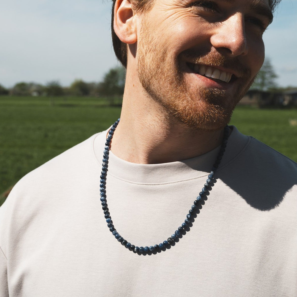 Royal Lapis Necklace (6mm) gedragen op een lichtgrijs t-shirt in het veld | Stoney Bracelets