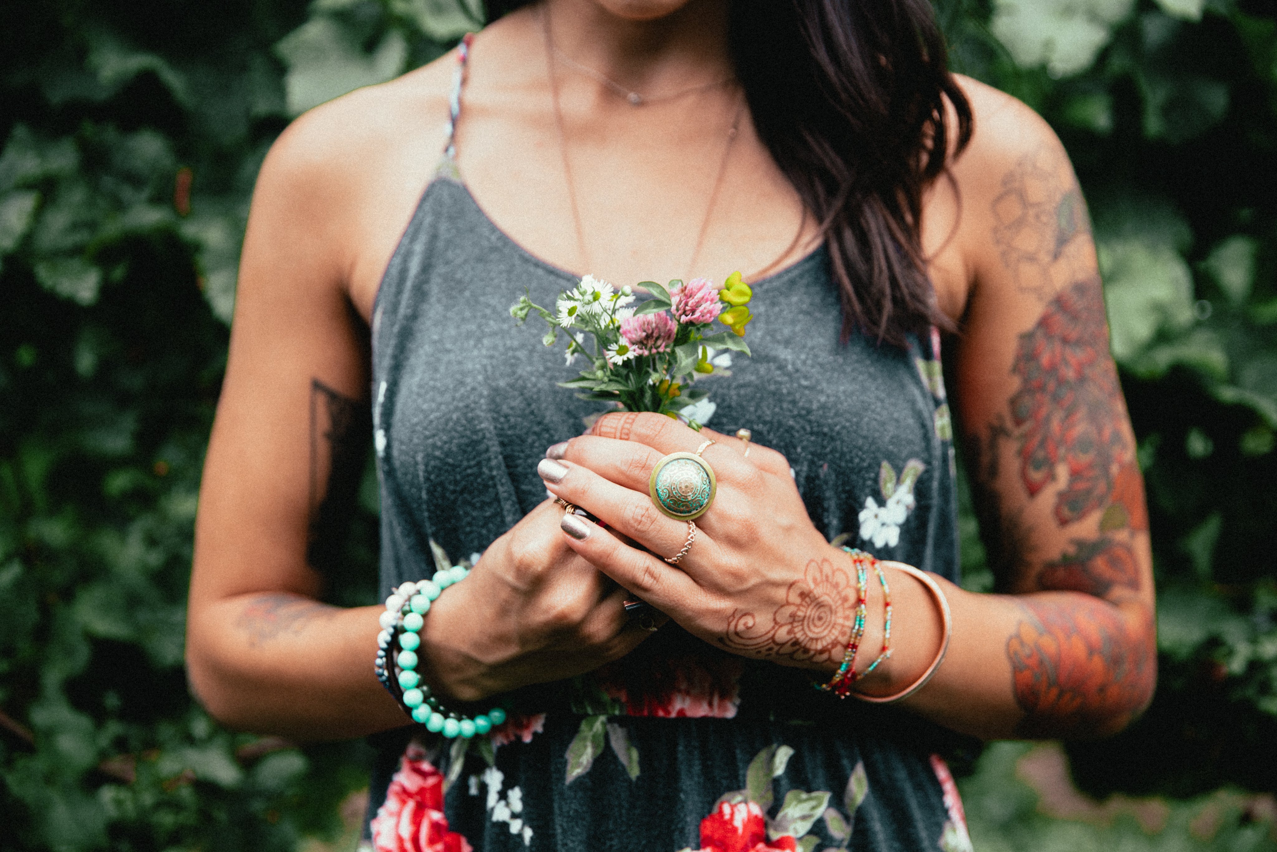 Een vrouw met tatoeages die een boeket bloemen vasthoudt.