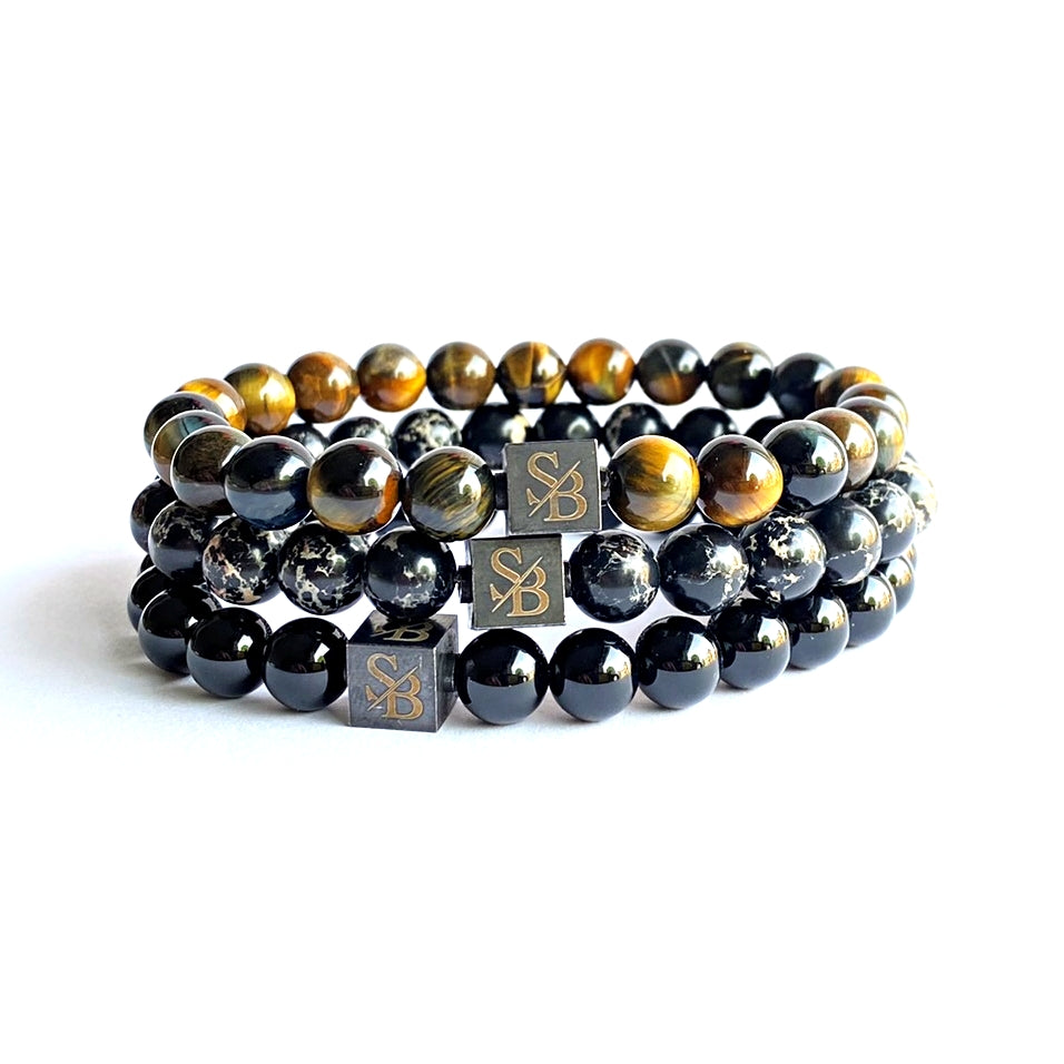 Een collectie zwarte en tijgeroogsteen Stoney Bracelets Bandit Set (8mm) armbanden.
