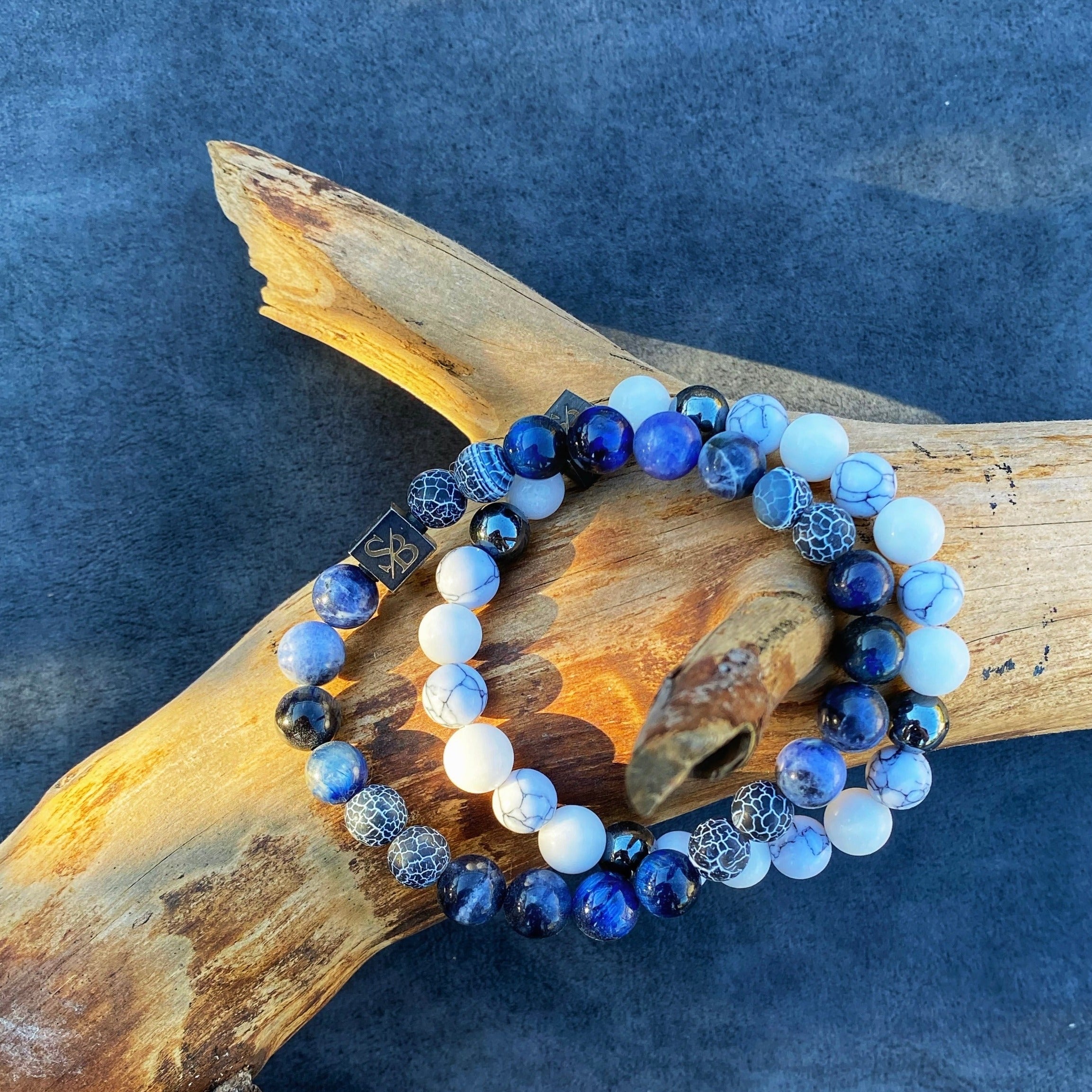 Twee Oceaan | Mixed Stones (8mm) armbanden met blauwe en witte kralen op een houten blok van Stoney Bracelets.