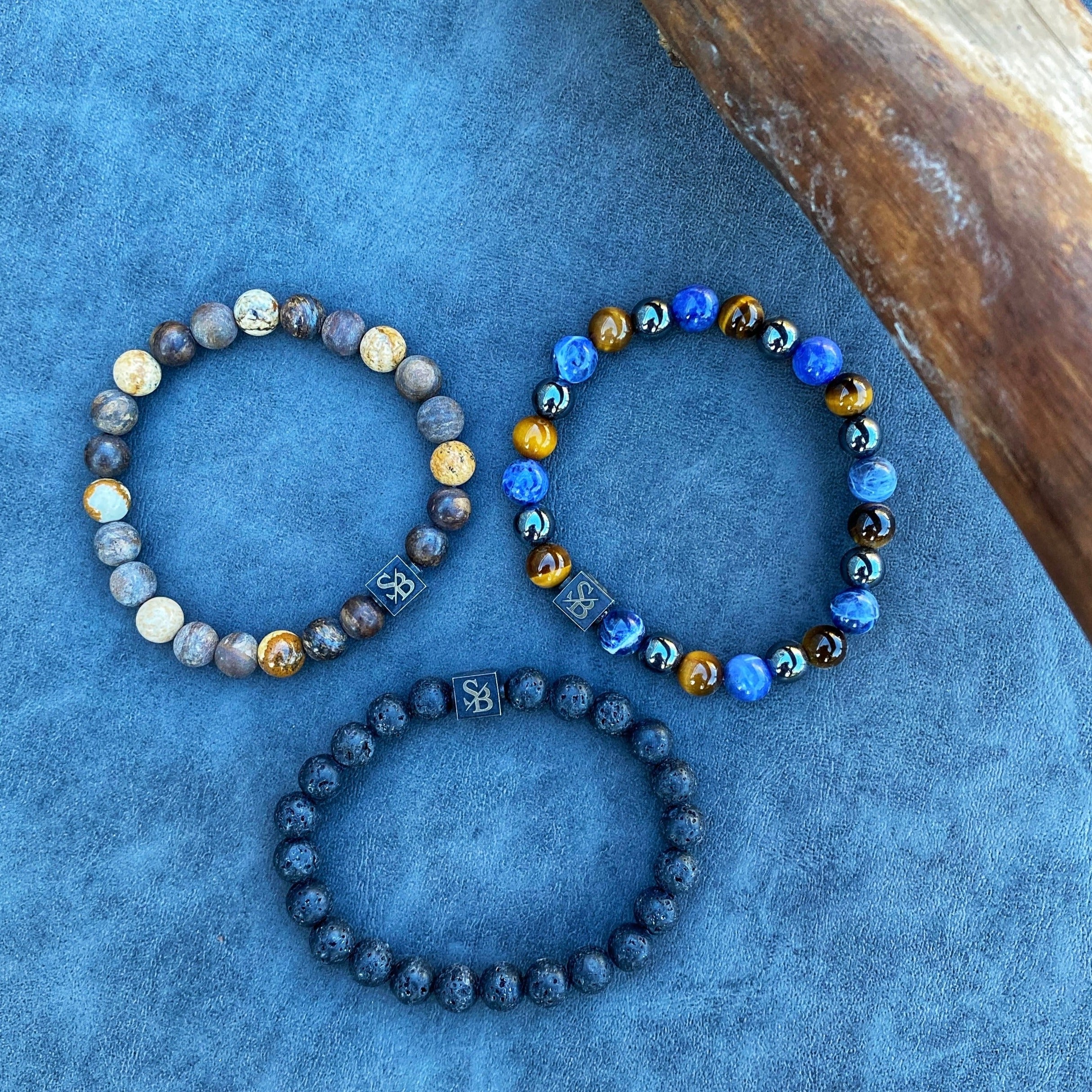 Drie regenwoud | Mixed Stones (8mm) armbanden op een blauwe achtergrond van Stoney Bracelets.
