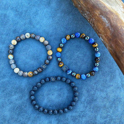 Drie Stoney Armbanden met Dessert Mixed Stones (8mm) op een blauwe achtergrond.