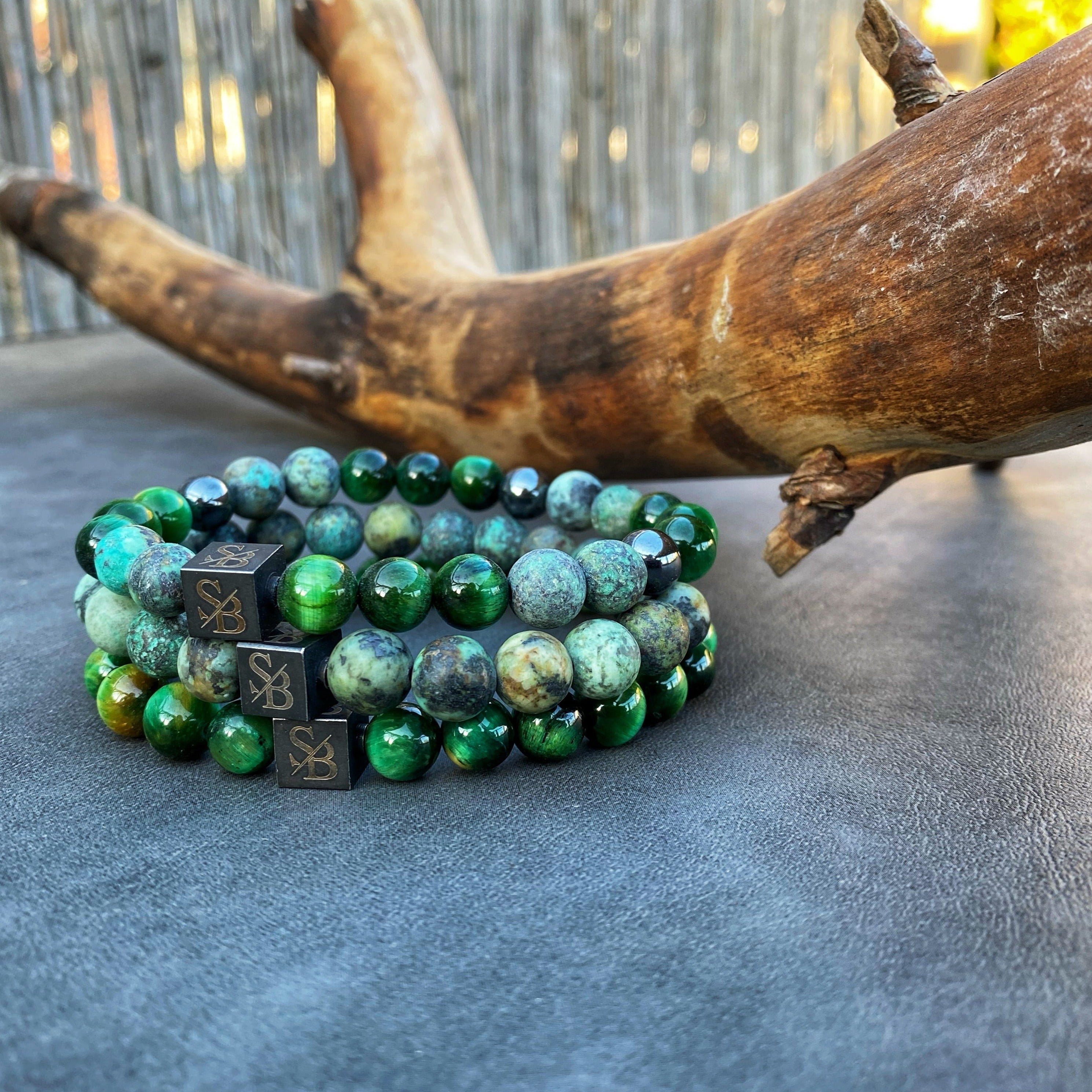 Een Stoney Bracelets armband met groene en zwarte Grass Set (8 mm) kralen bovenop een boomstronk.
