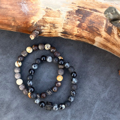 Een paar Dessert | Mixed Stones (8mm) armbanden van Stoney Bracelets op een houten stam.