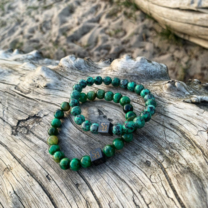 Twee groene en zwarte Stoney armbanden uit de Nature Set (8 mm) zittend op een boomstam.