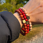 De hand van een vrouw houdt een rood-witte houten armband vast uit de Stoney Bracelets Triple Red Set (8 mm).