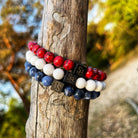 Beschrijving: Een Dutch Set (8mm) armband met rode, witte en blauwe kralen op een boomstronk van Stoney Bracelets.