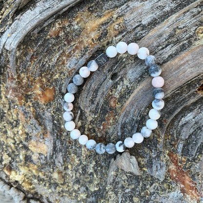 Een roze en witte Matte Zebra Stones (6 mm) armband op een stuk hout van Stoney Bracelets.