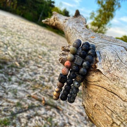 Een paar Stoney Bracelets Earth Set armbanden zittend op een boomtak.