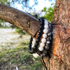 Twee zwart-witte Frosted Zebra Stones (8 mm) Stoney-armbanden die aan een boom hangen.