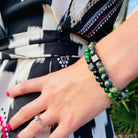 Een vrouw met een groene Stoney Bracelets Groene Tijgeroogstenen (6 mm) armband.