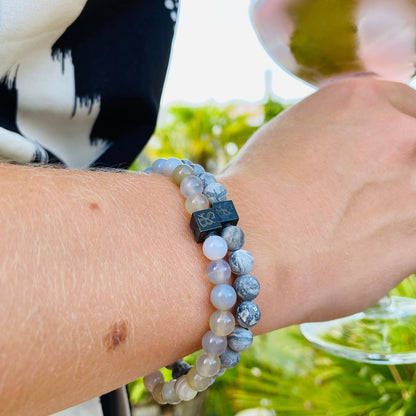 Een vrouw houdt een glas wijn vast terwijl ze een Stoney Bracelets Matte Jasper Stones (6 mm) armband draagt.