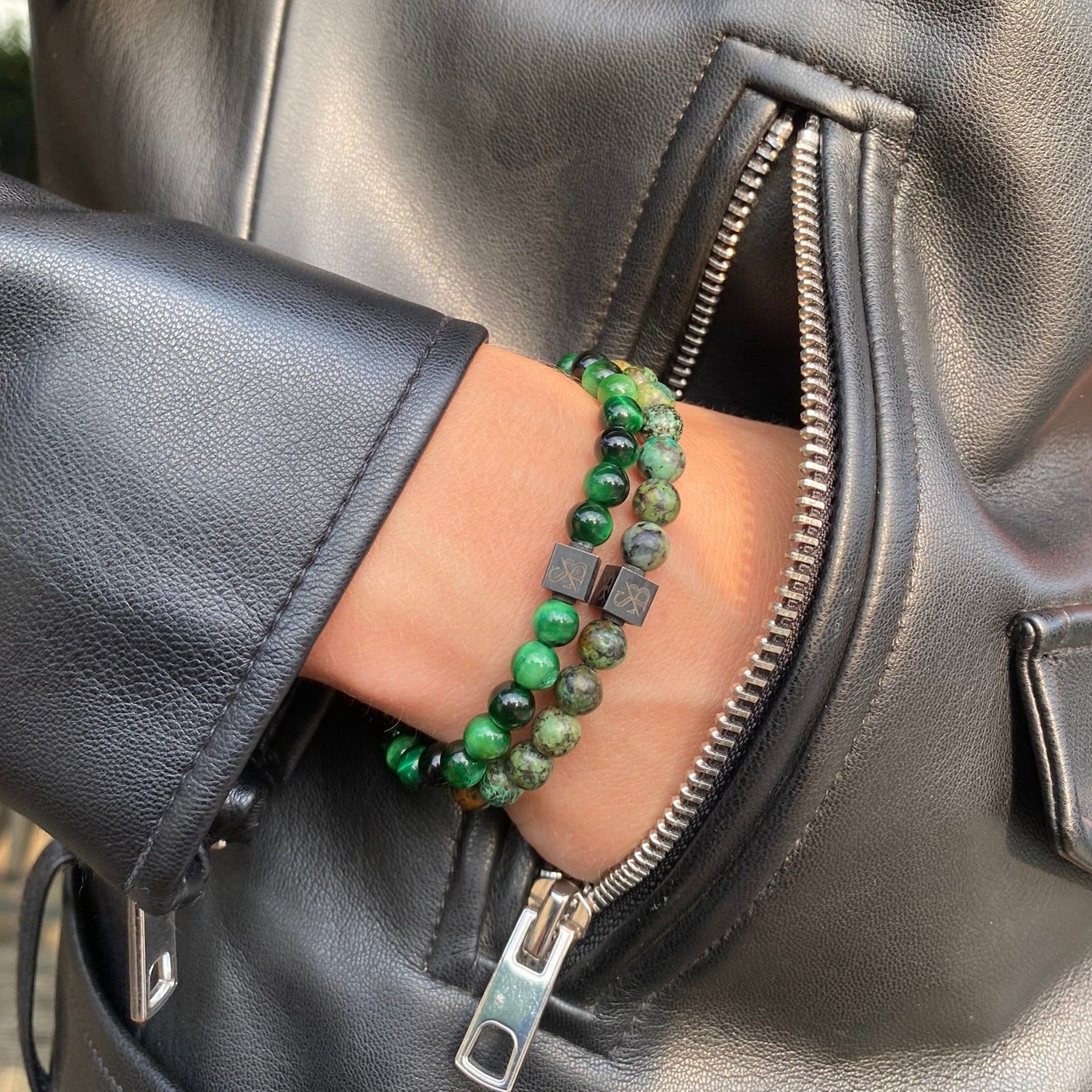 Een vrouw in een leren jasje draagt Stoney Bracelets groene Tiger Eye Stones (6mm) armbanden.