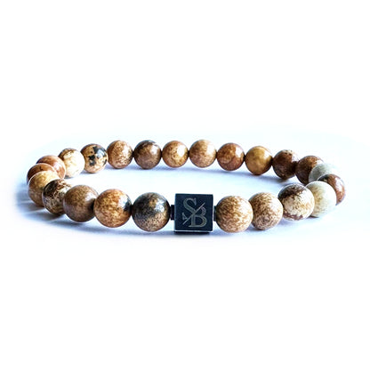 Een Stoney Armband met Dessert Jasper Stenen (8mm) en een zwart vierkant erop.