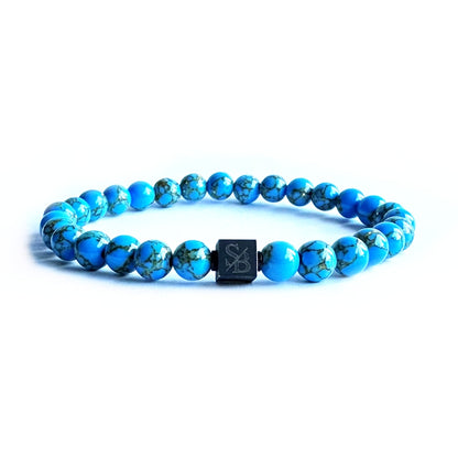 Een gouden turquoise stenen (6 mm) Stoney armband met een zwart vierkant erop.