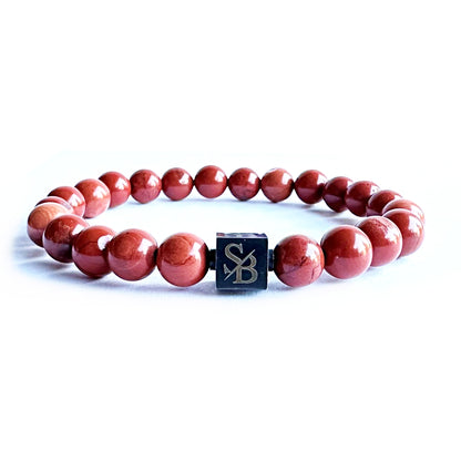 Een Stoney Bracelets armband met rode sesamstenen (8 mm) en een zwart vierkant erop.