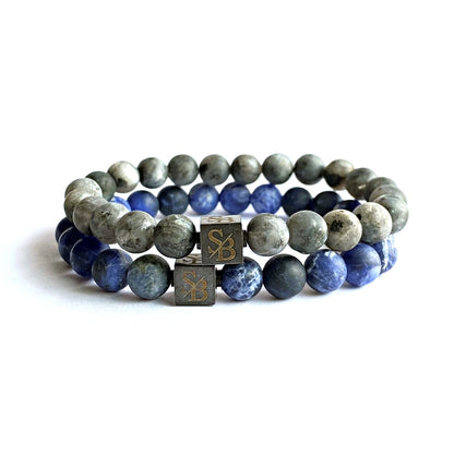 Een paar Stoney Bracelets Matte Lapis Lazuli-sets (8 mm) met de initialen erop gegraveerd.