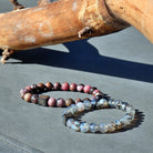 Twee Stoney Bracelets' Dragon Vein Stones (8 mm) zitten bovenop een boomstam.