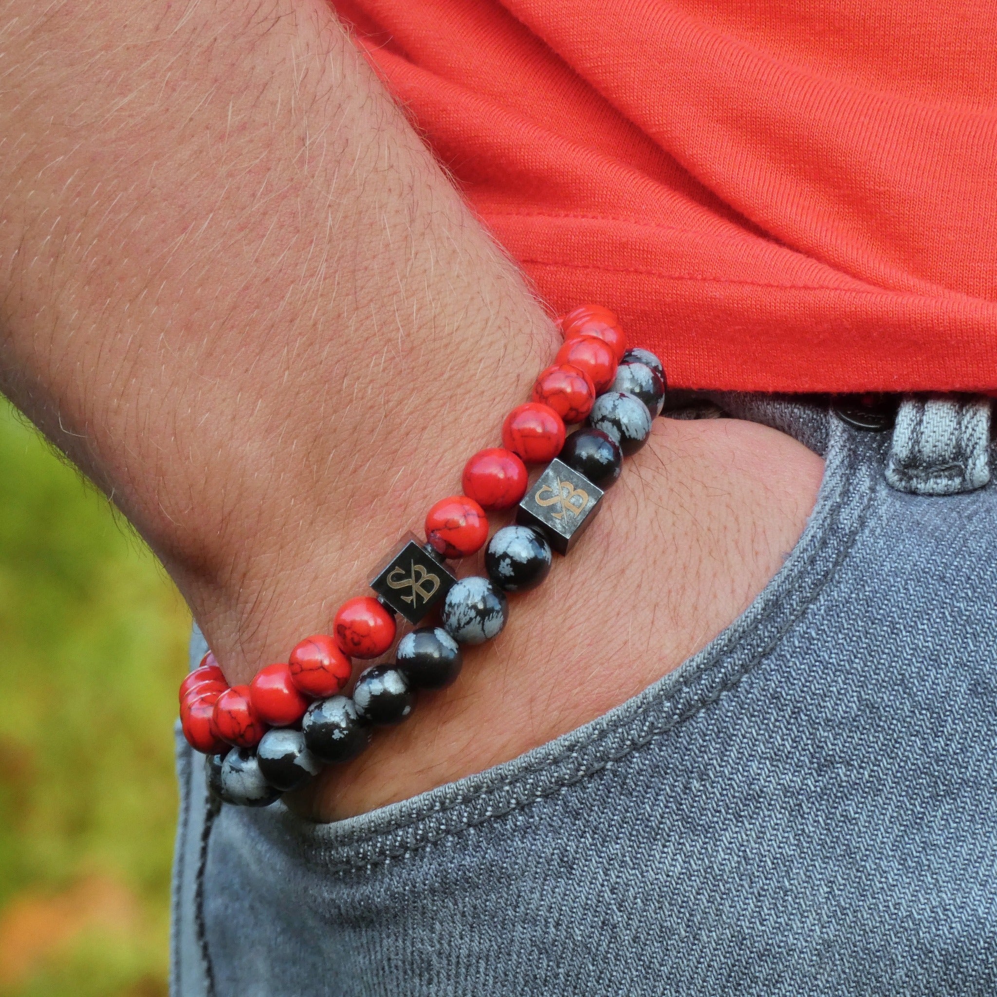 Een man met een Stoney Bracelets Red vs Black Set (8 mm) kralenarmband.